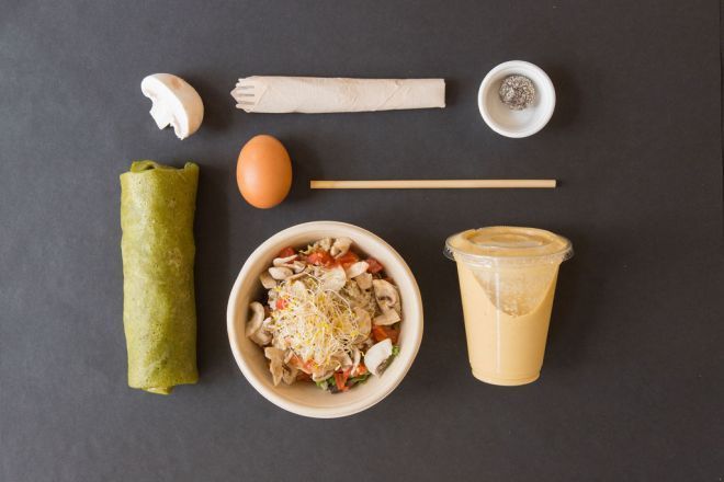 Una mesa cubierta con un tazón de comida, una tortilla, un huevo y una taza de salsa.