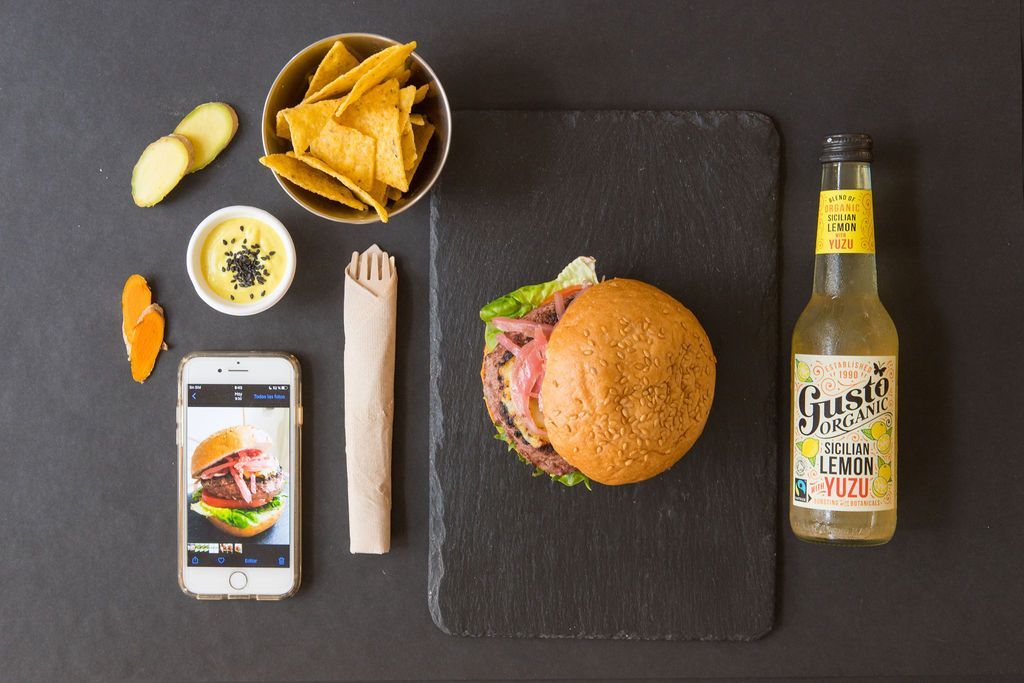 Una botella de limonada junto a una hamburguesa y patatas fritas