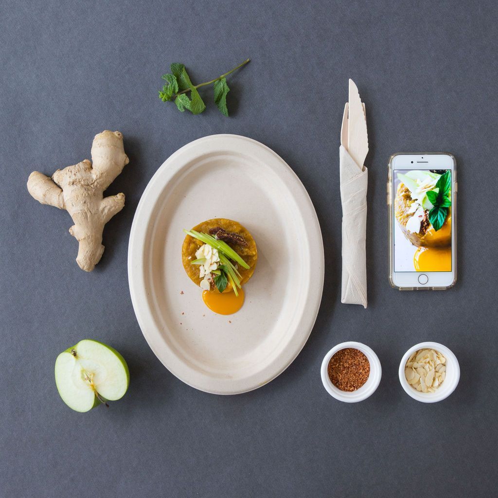 Un plato de comida está rodeado de ingredientes y un teléfono celular.