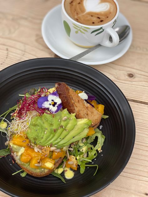 Un plato de comida junto a una taza de café en una mesa de madera.