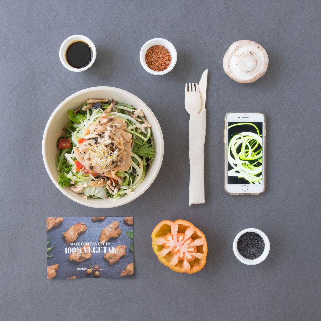 Un plato de comida está rodeado de condimentos y un teléfono celular.