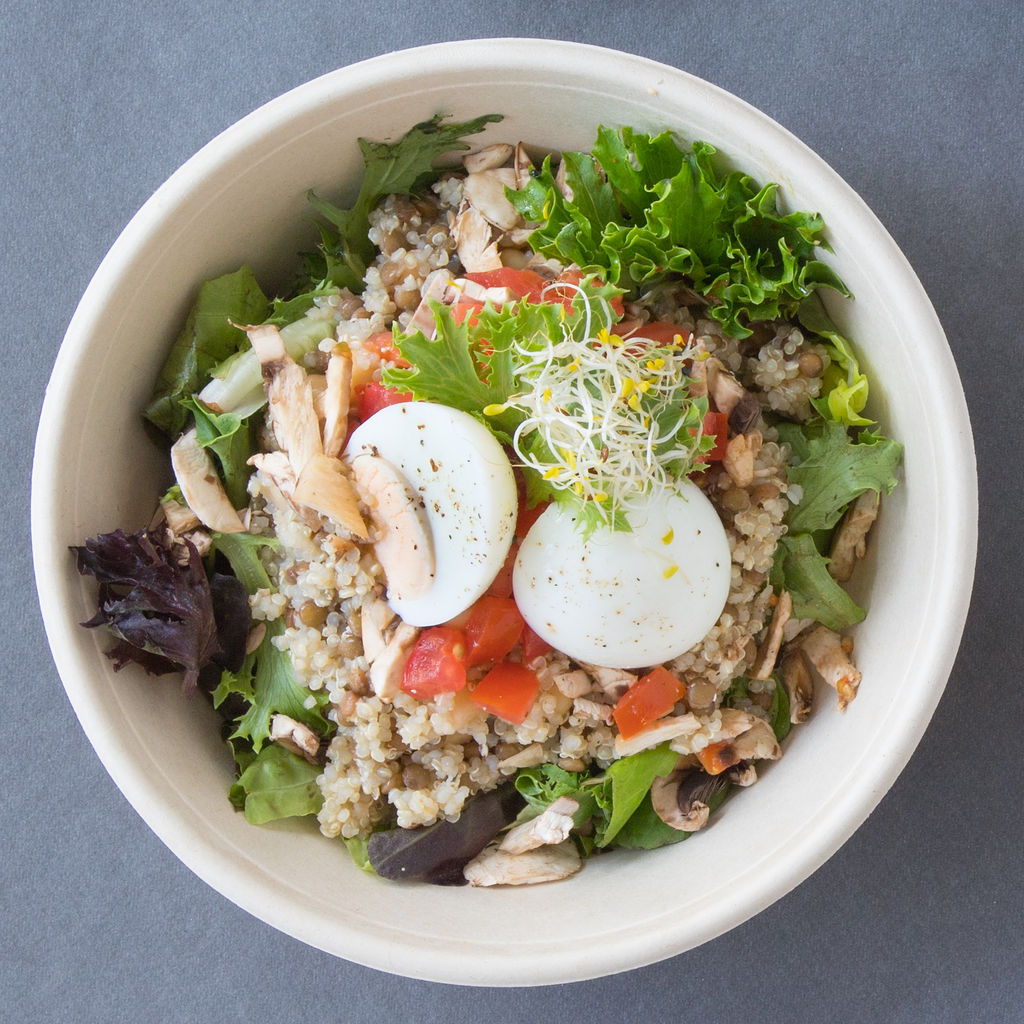 Un tazón de comida con arroz y verduras en una mesa.