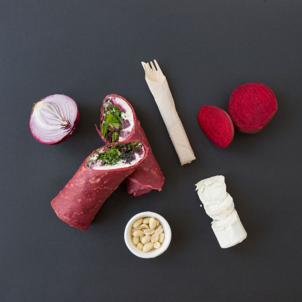 Un wrap rodeado de verduras y un tenedor de madera.