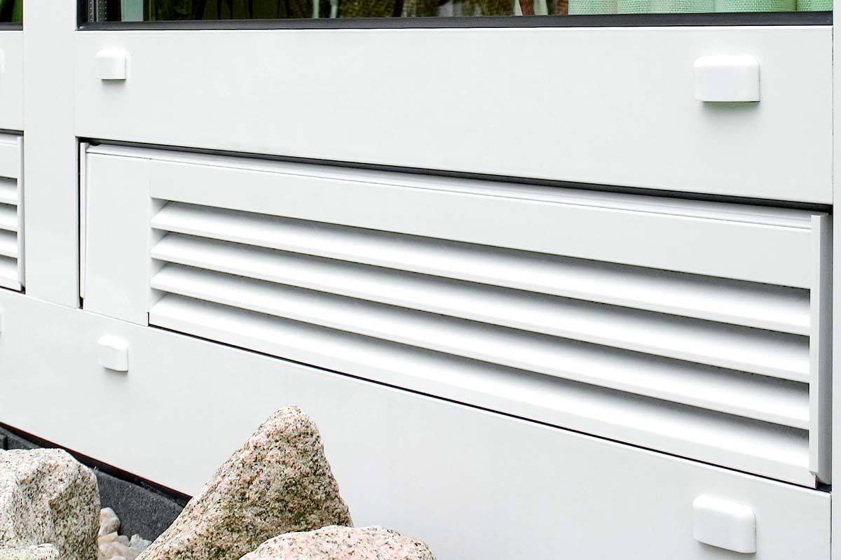 Eine weiße Tür mit einem Lüftungsgitter an der Seite.