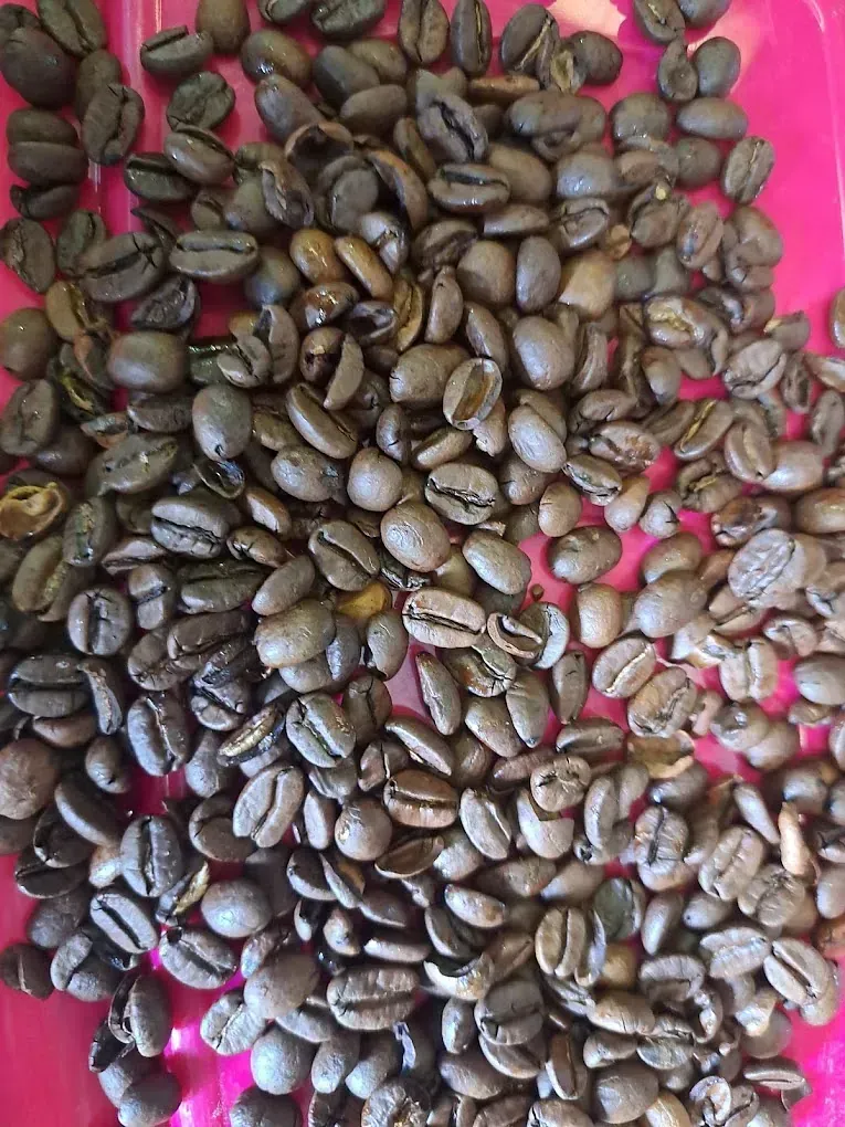 Un montón de granos de café en un plato rosa.