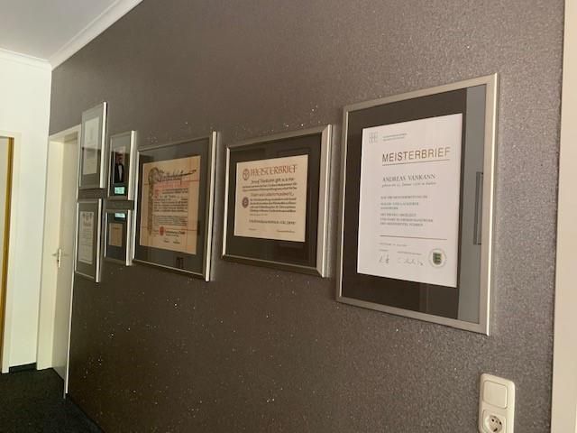 Ein Flur mit einer Reihe gerahmter Zertifikate an der Wand.
