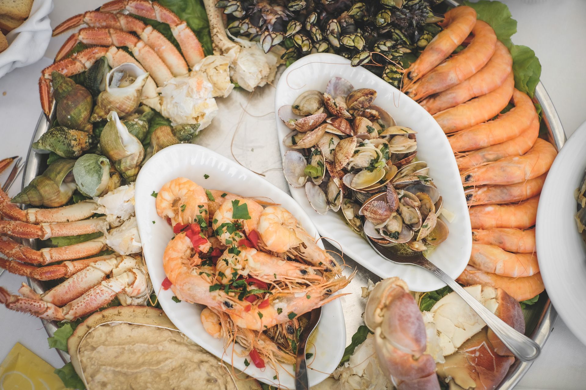 Plateau de fruits de mer avec crevettes, pattes de crabe, moules et poisson grillé sur des plats de service blancs
