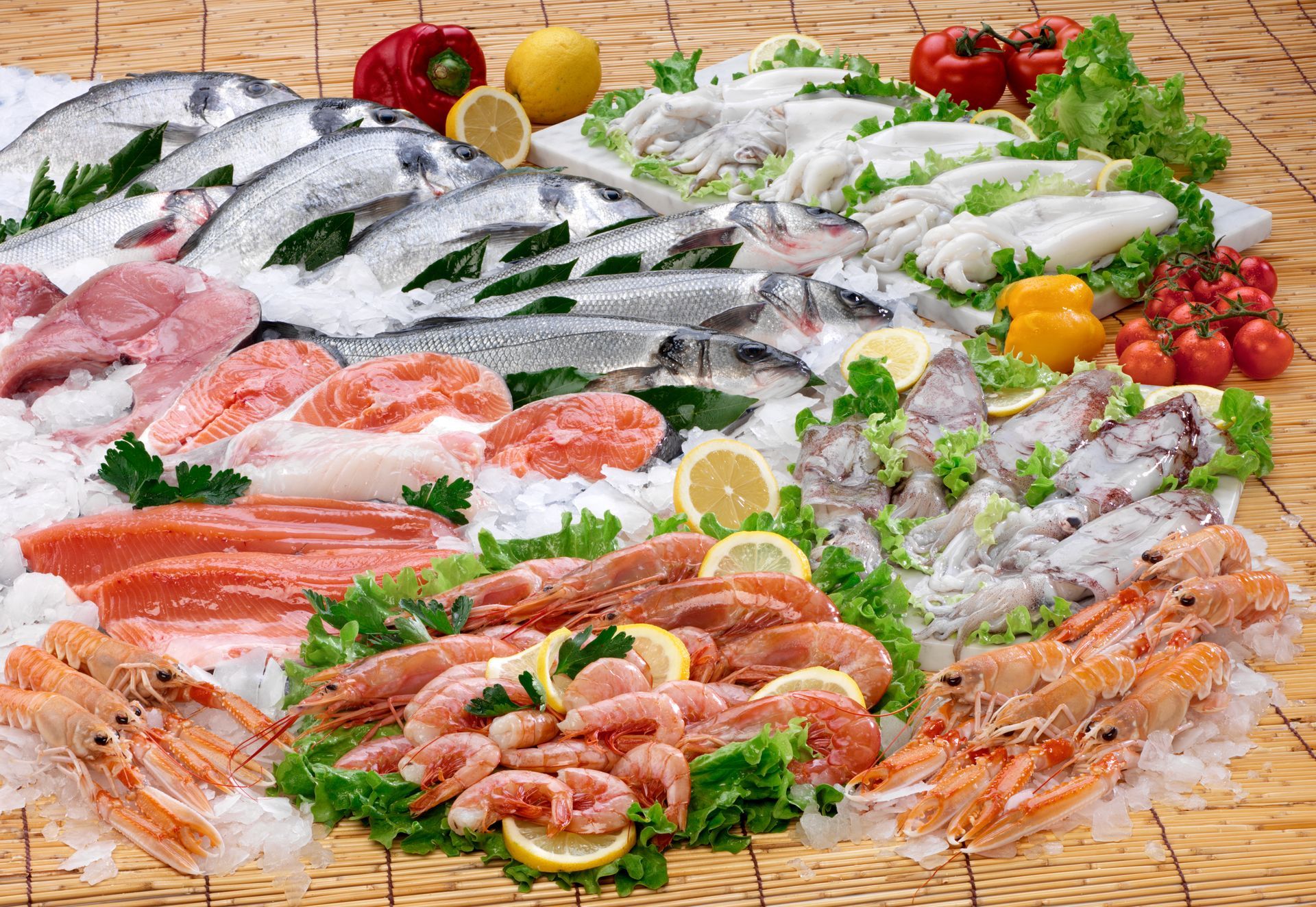 Assortiment de poissons et fruits de mer frais disposés sur un présentoir avec du citron et de la verdure.