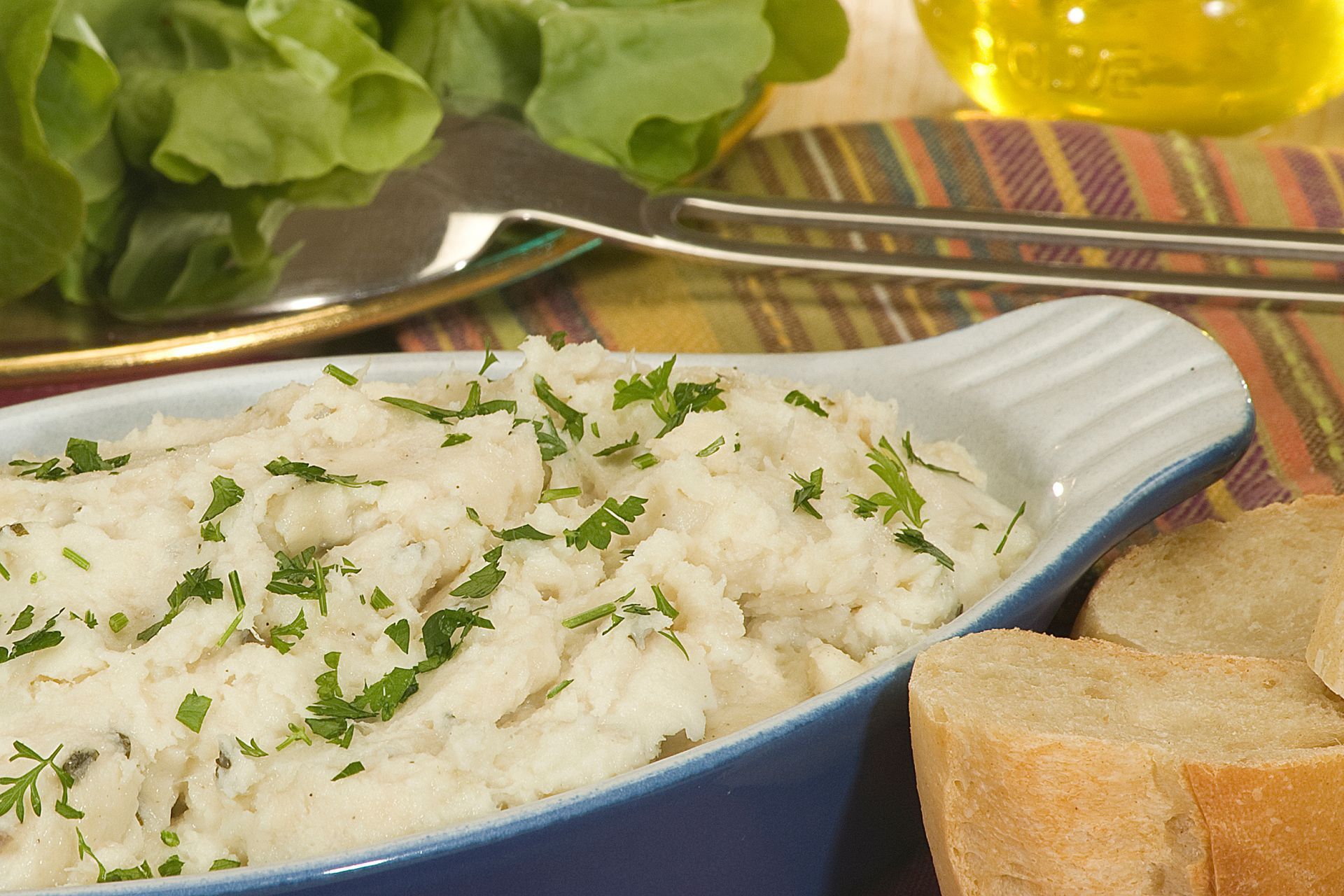 Du riz blanc aux herbes dans un plat bleu, accompagné de pain et de salade sur une table.