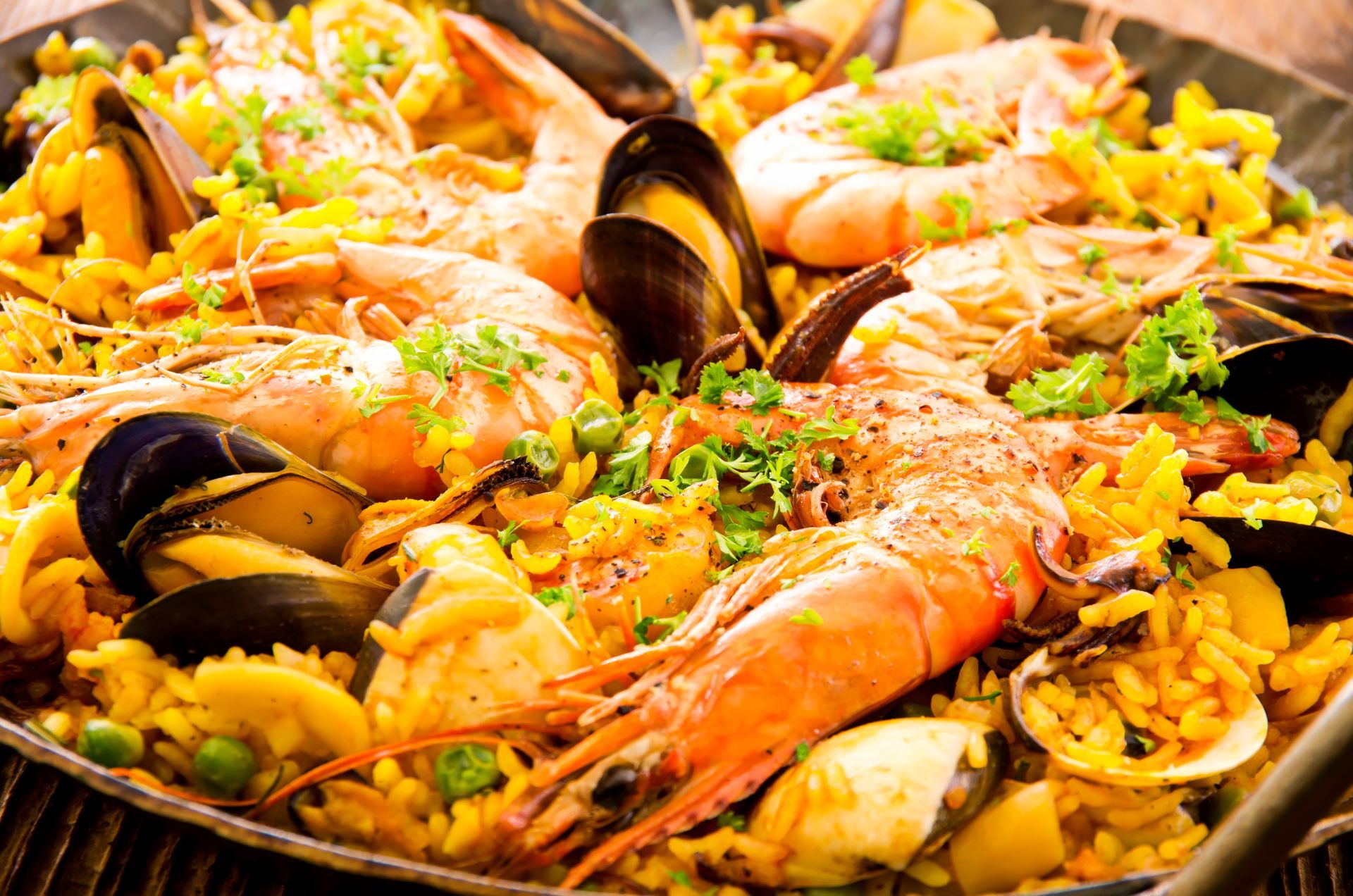 Paella aux fruits de mer avec crevettes, moules et riz dans une grande poêle, garnie d'herbes aromatiques.