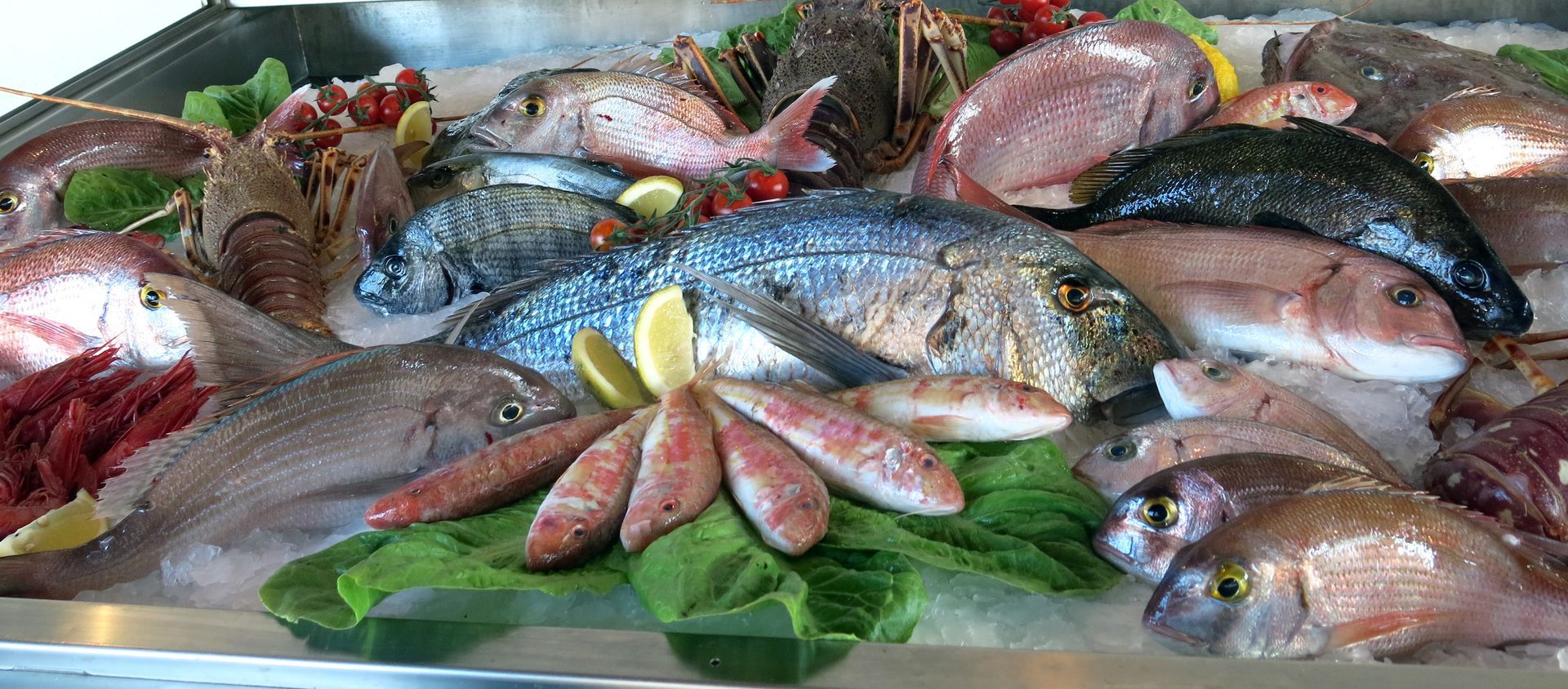 Des poissons entiers et des fruits de mer disposés sur des feuilles vertes
