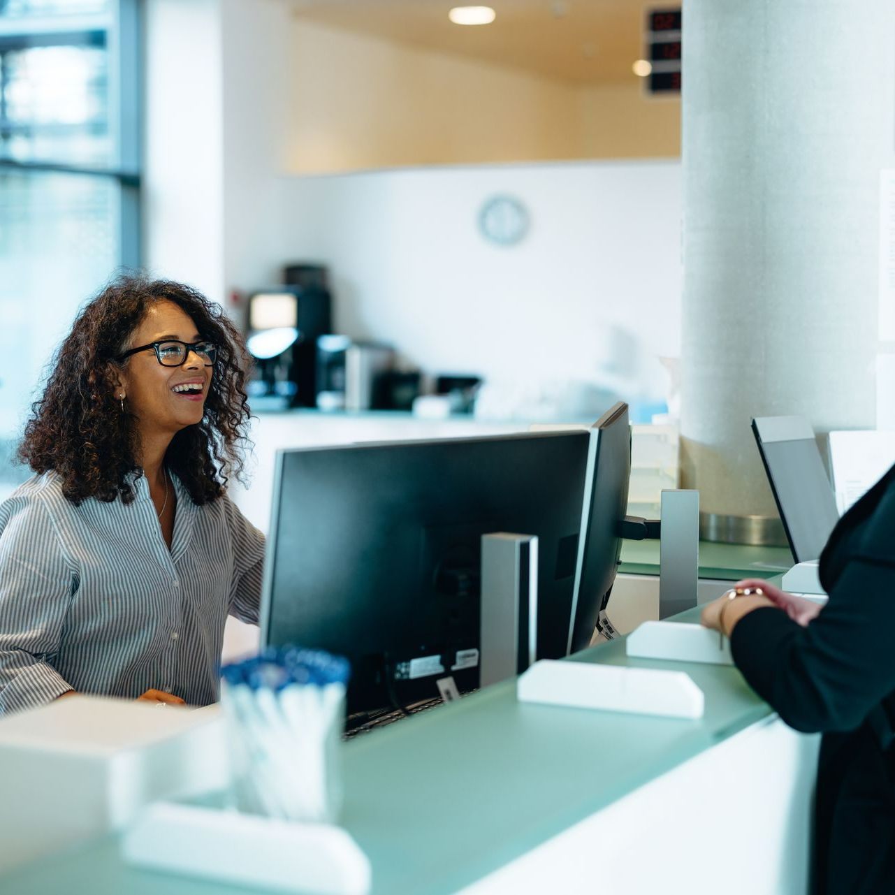 Une personne qui sourit en accueillant des clients