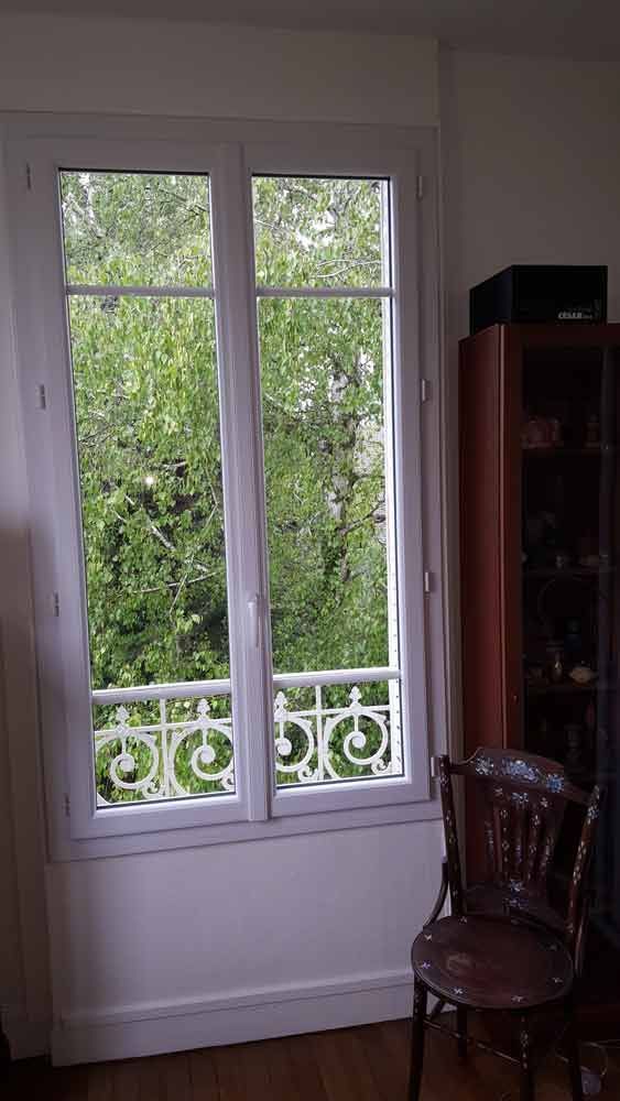 Fenêtre à cadre blanc donnant sur une végétation luxuriante. 