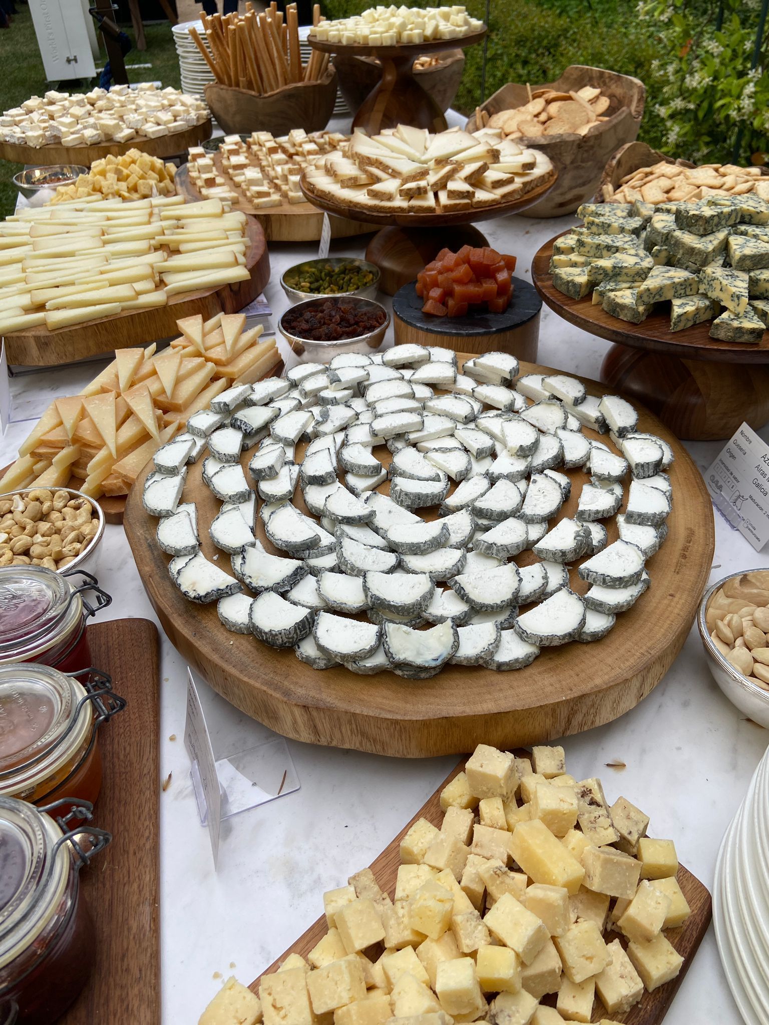 Estanterías con ruedas de queso curado, de distintos tamaños y color dorado, en un almacén de madera.