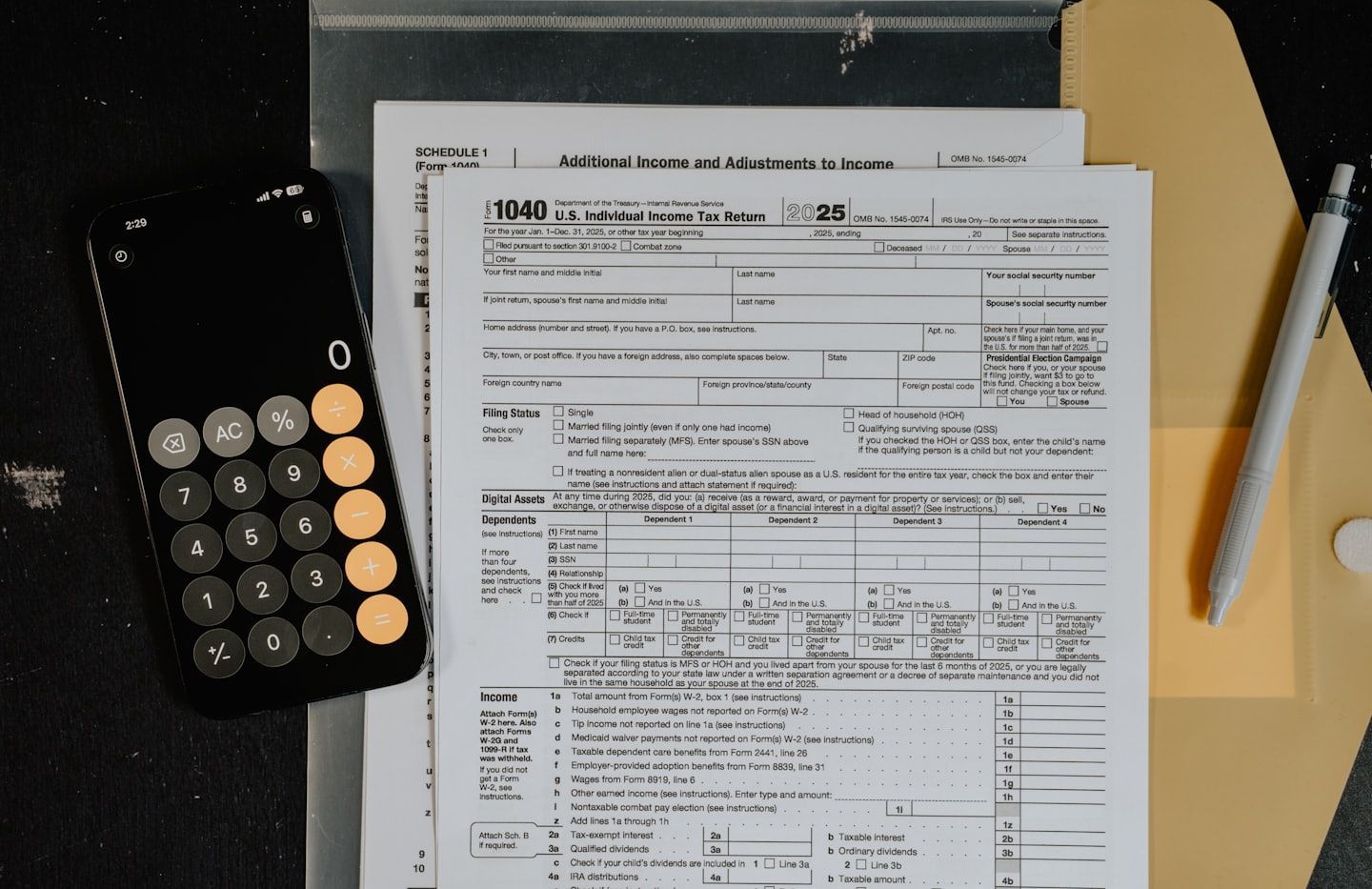 Escritorio con formularios de impuestos, calculadora, carpeta y bolígrafo en un portapapeles.