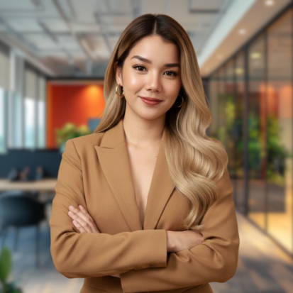 Woman in a navy blazer with arms crossed, smiling in an office.