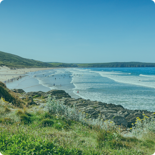 A beach with a lot of people on it and a large body of water.
