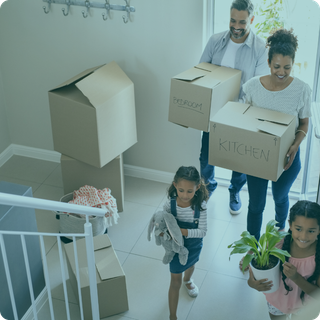 A family is moving into a new home carrying boxes and potted plants.