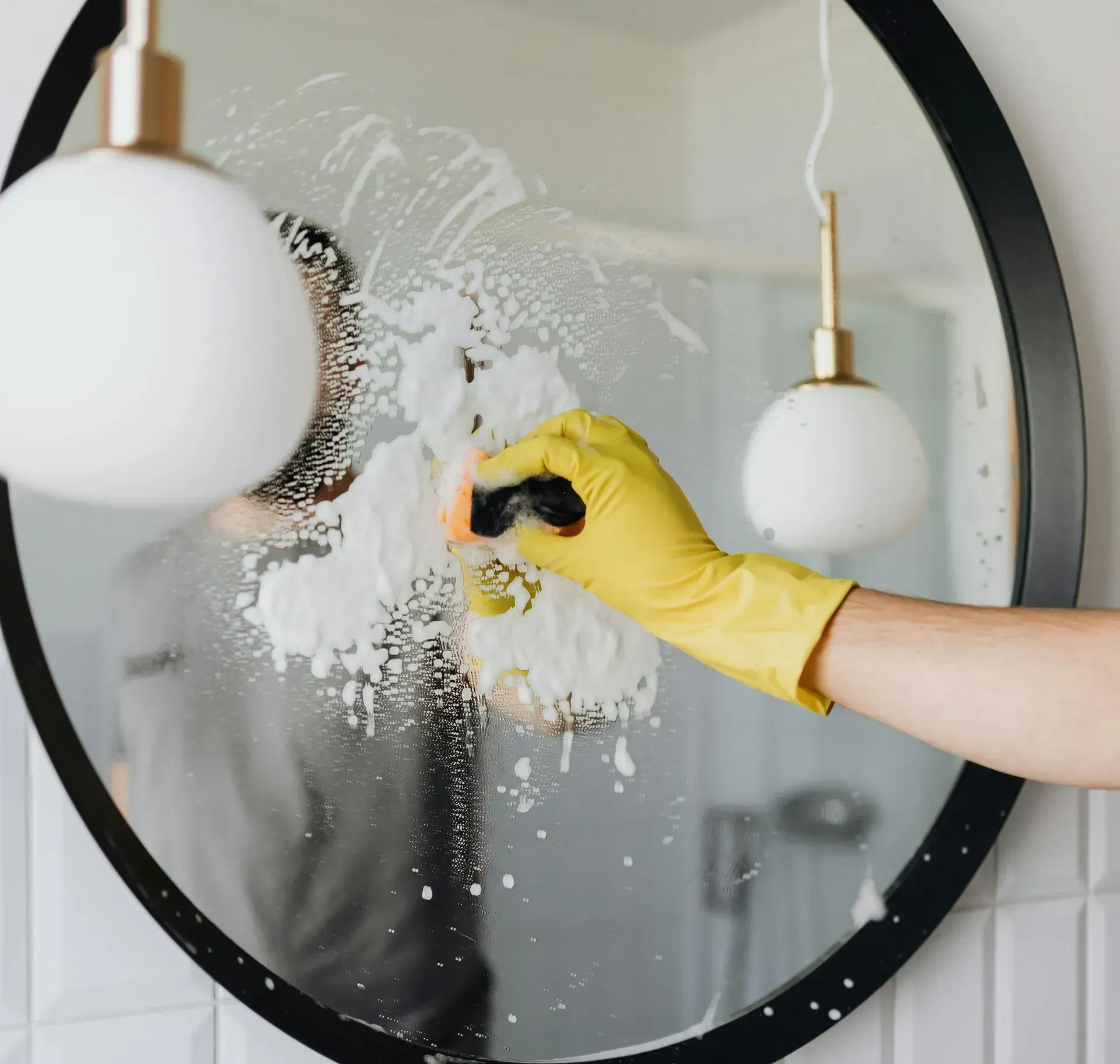 Uma mulher sorridente passa o aspirador de pó no chão claro de uma sala de estar. 