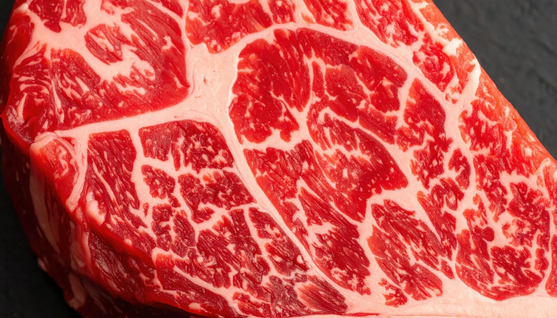 Gros plan d'un steak de bœuf cru persillé, avec des veines de viande rouge et de gras blanc.