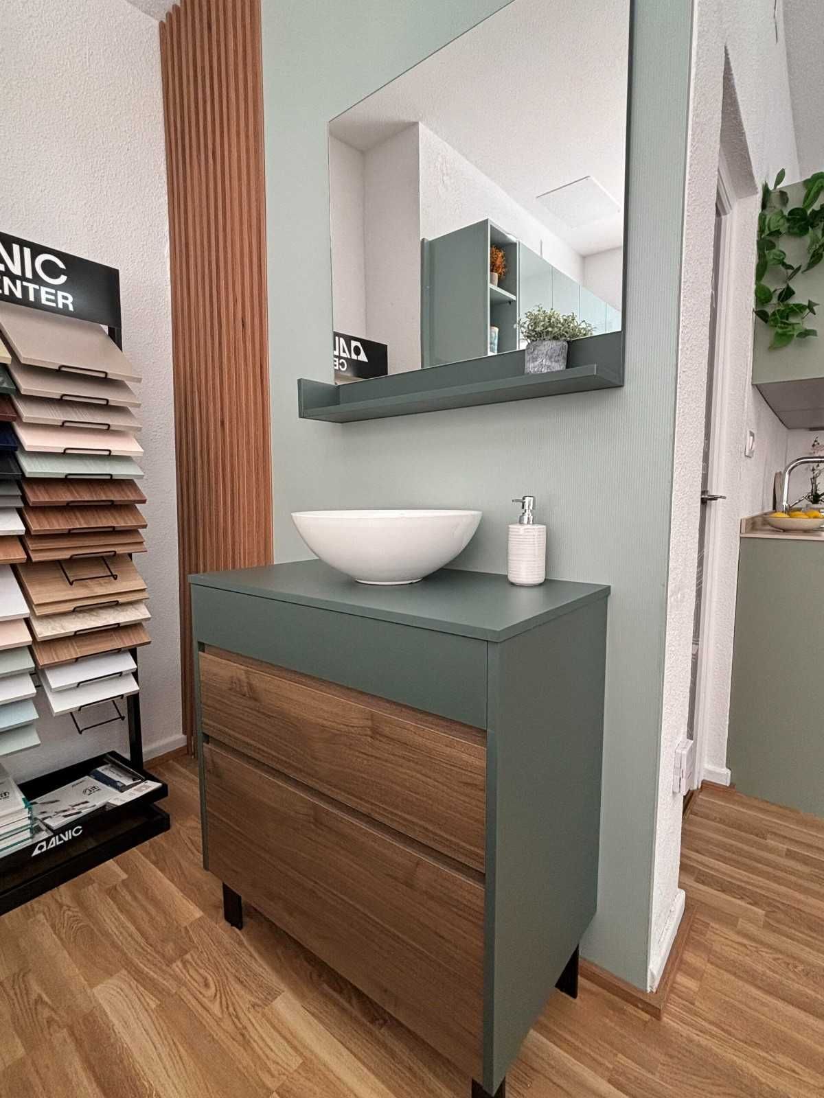 Mueble de baño con lavabo blanco, cajones de madera y mueble verde.