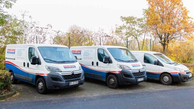 Drei Lieferwagen stehen nebeneinander am Straßenrand.