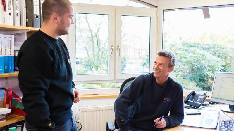 Zwei Männer stehen nebeneinander in einem Büro und unterhalten sich
