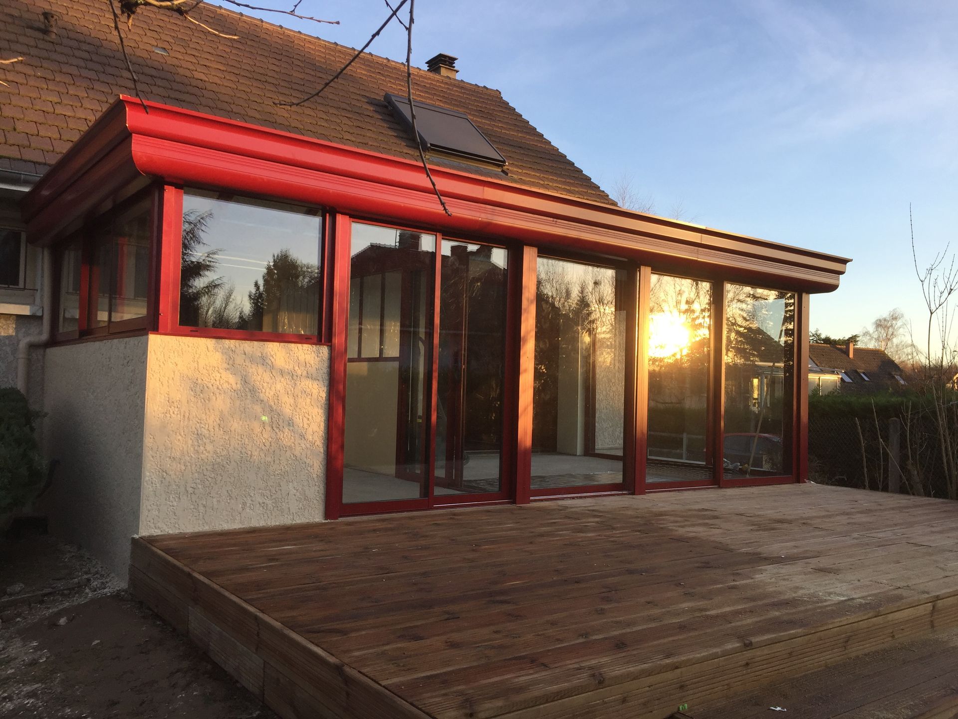 Véranda rouge avec un coucher de soleil se reflétant sur la vitre 