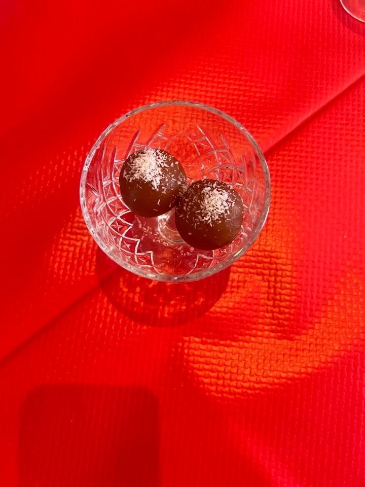 Bol en verre transparent avec deux truffes au chocolat sur un fond de tissu texturé rouge vif