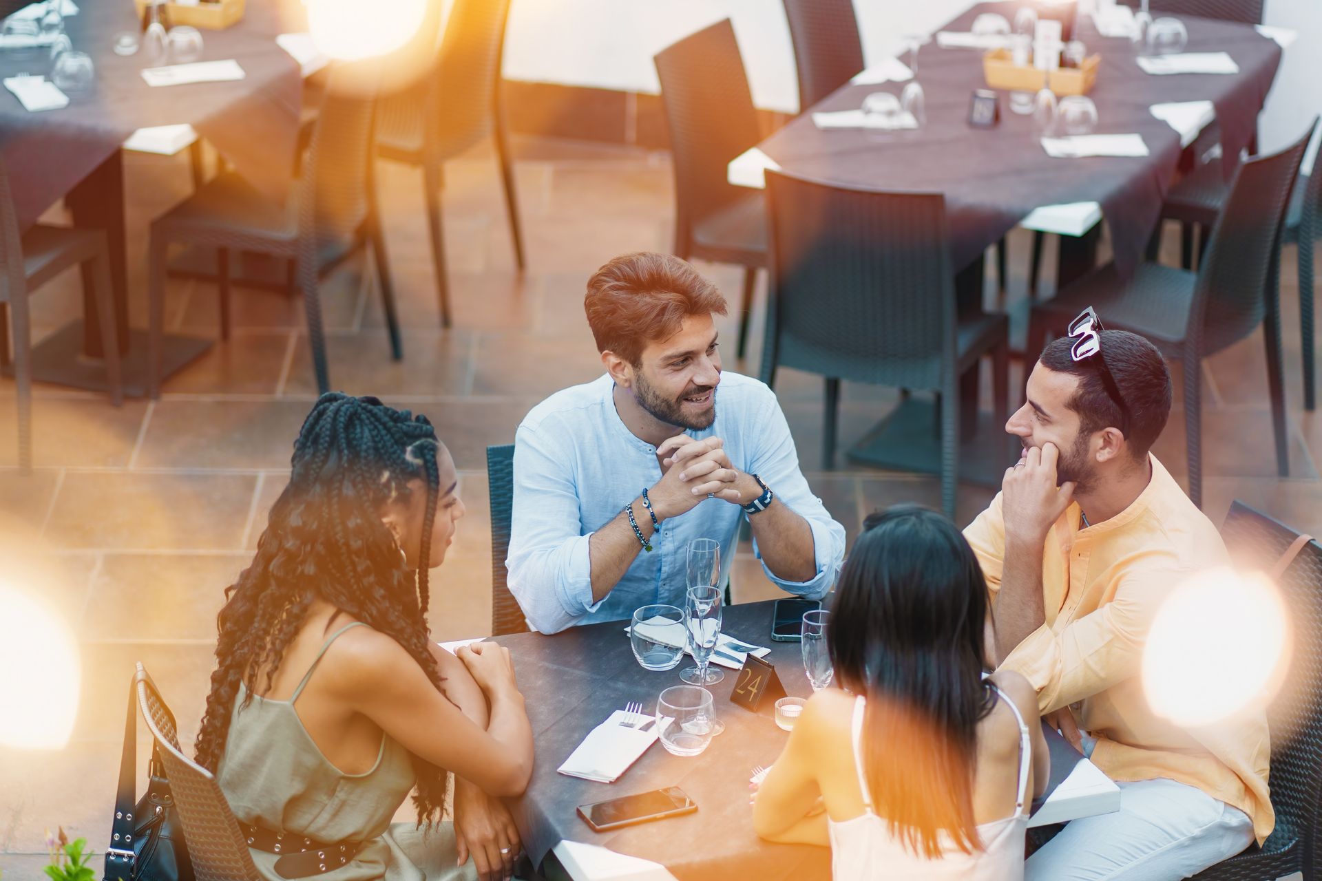 Quatre amis assis à une table de restaurant discutent entre eux.