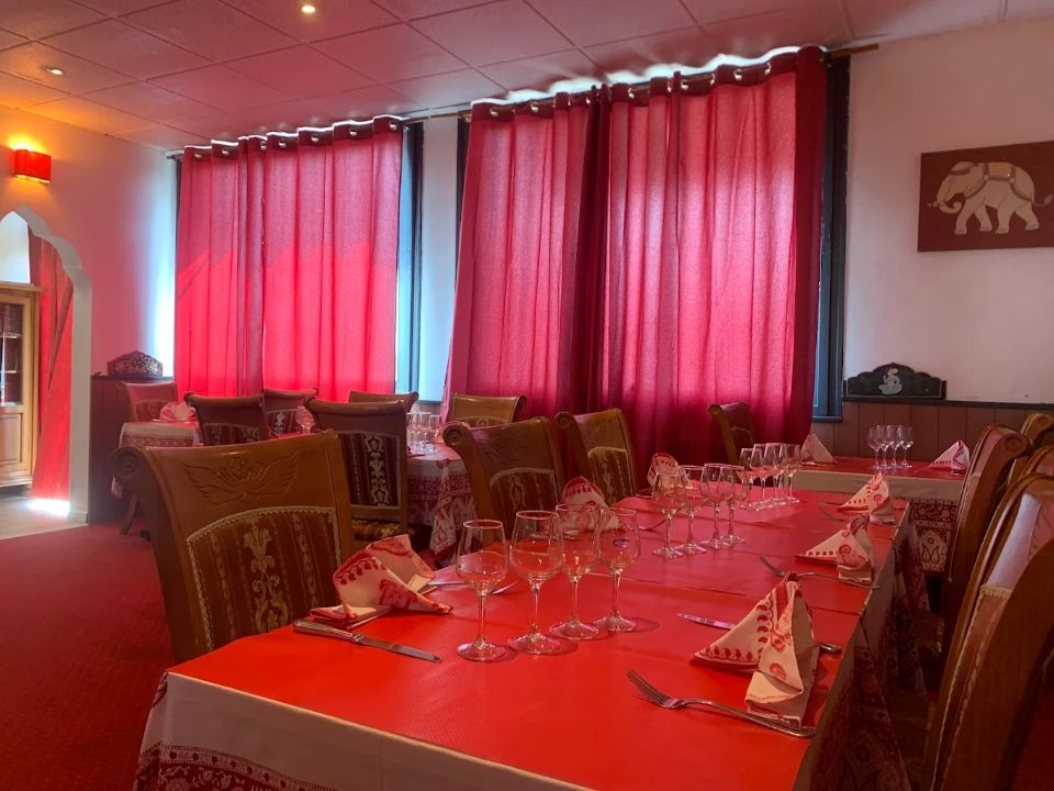 Nappes rouges et tables dressées dans un restaurant à l'éclairage tamisé, avec des rideaux rouges.