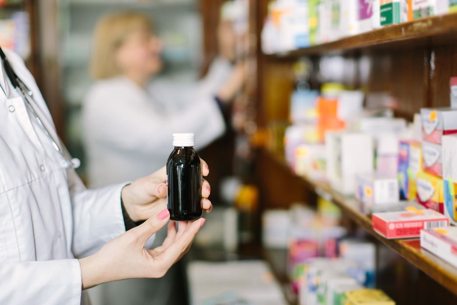 Una farmacéutica sostiene un frasco de medicamentos en una farmacia.