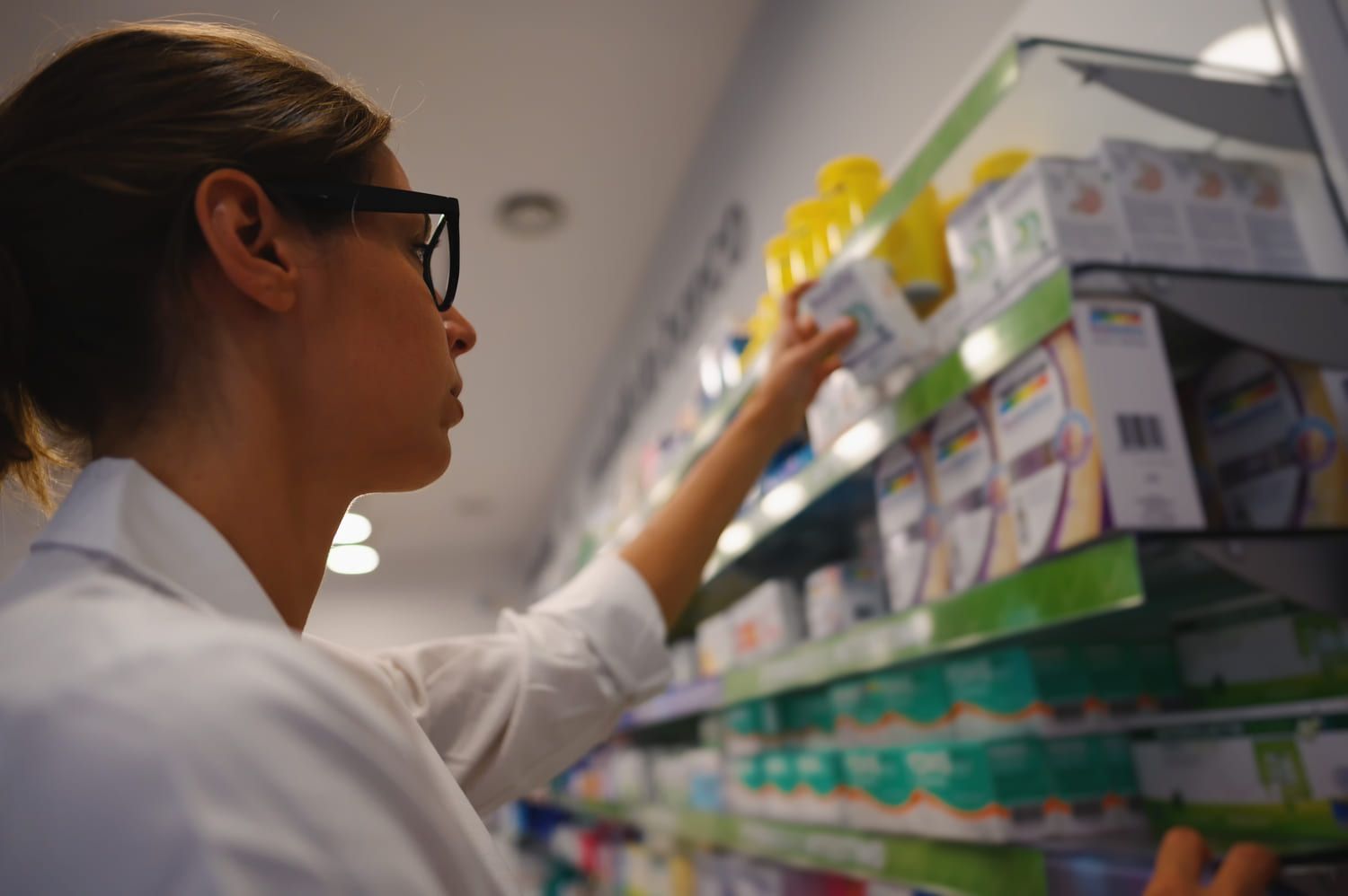 Una mujer está mirando un estante en una farmacia.