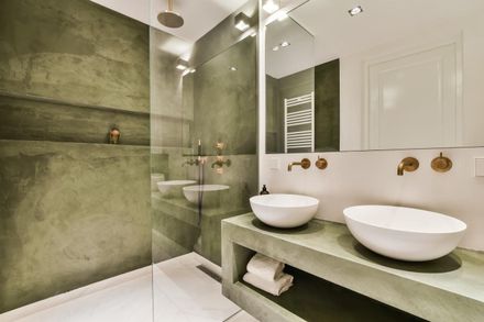 Un baño moderno con tocador de doble lavabo con encimeras de piedra y ducha a ras de suelo con paredes texturizadas