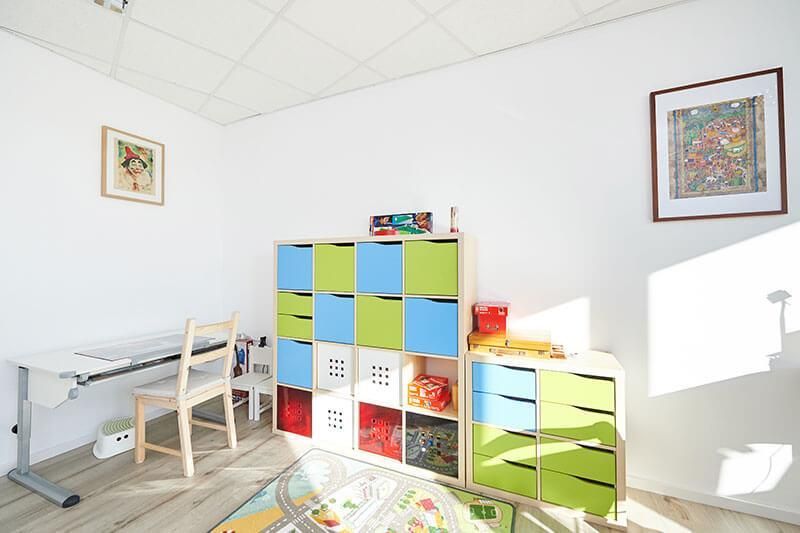Ein Kinderzimmer mit Schreibtisch, Stuhl, Kommode und Regalen