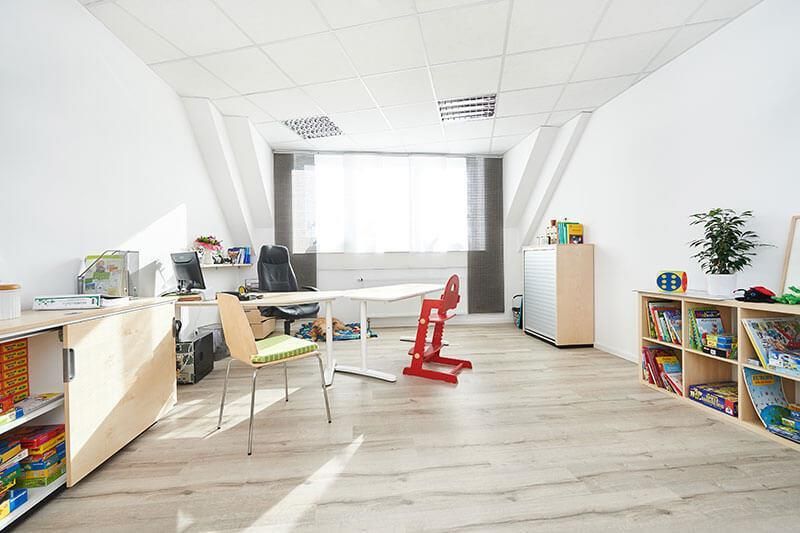 Ein Raum mit einem Tisch, Stühlen und Regalen voller Spielsachen.