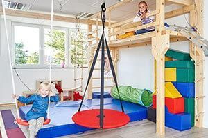 Ein Mädchen sitzt in einem Spielzimmer auf einer Schaukel.