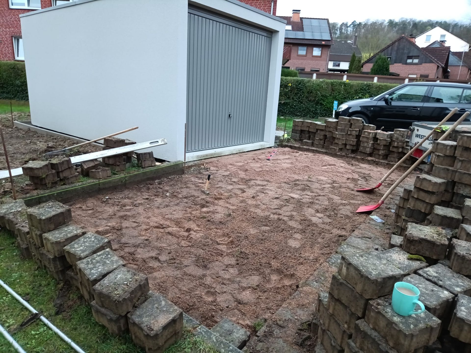 Vor einer Garage wird eine Ziegelmauer gebaut.