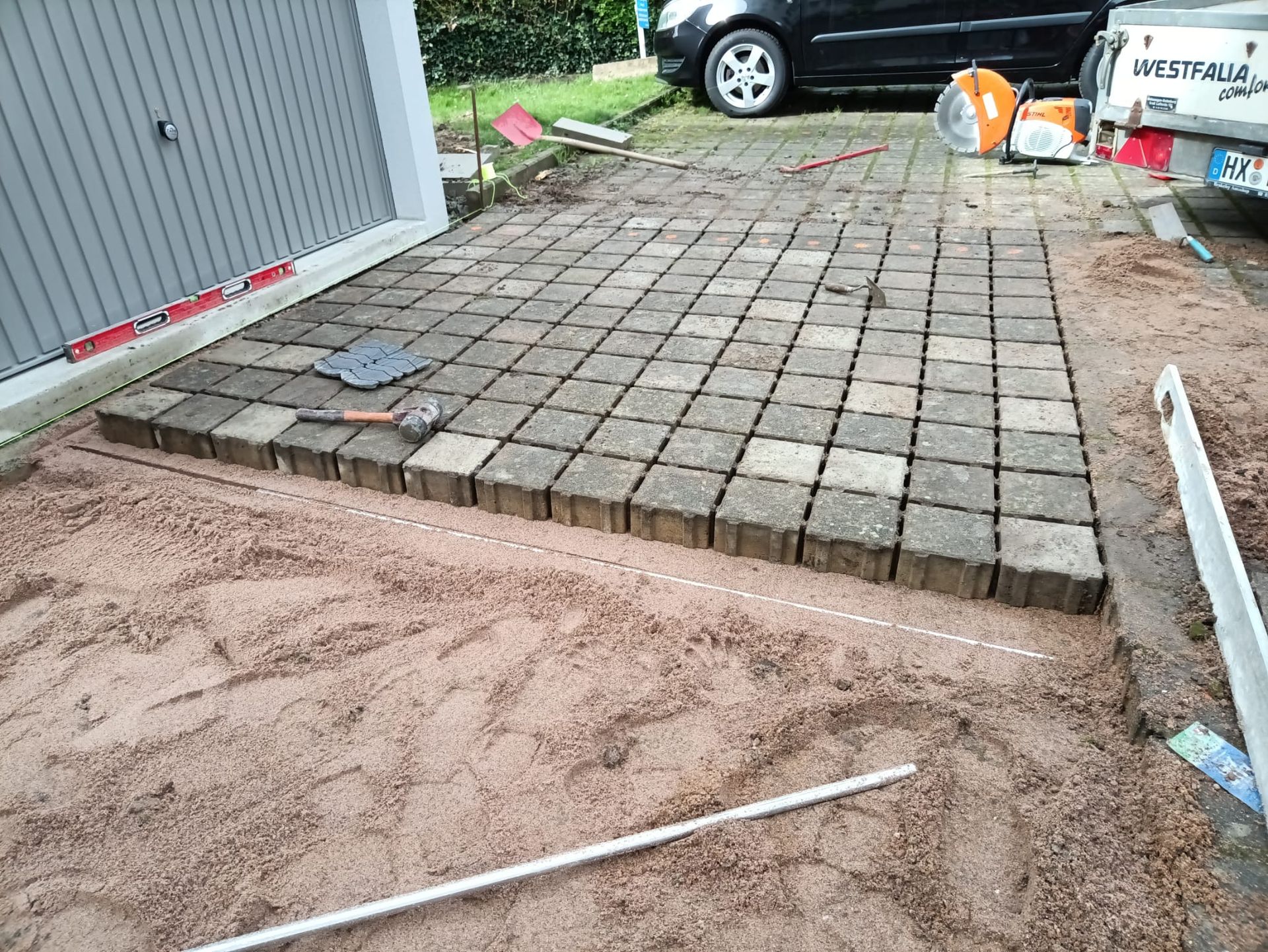 Neben einer Garage wird eine gepflasterte Auffahrt gebaut.