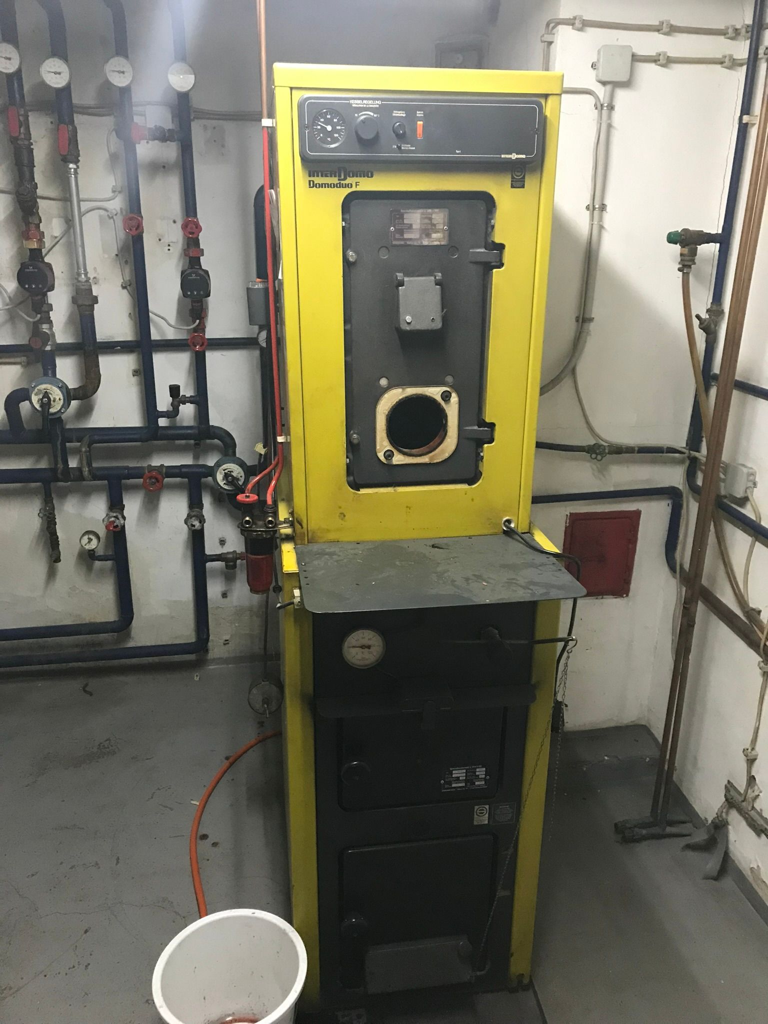 Ein gelber und schwarzer Kessel in einem Raum mit Rohren