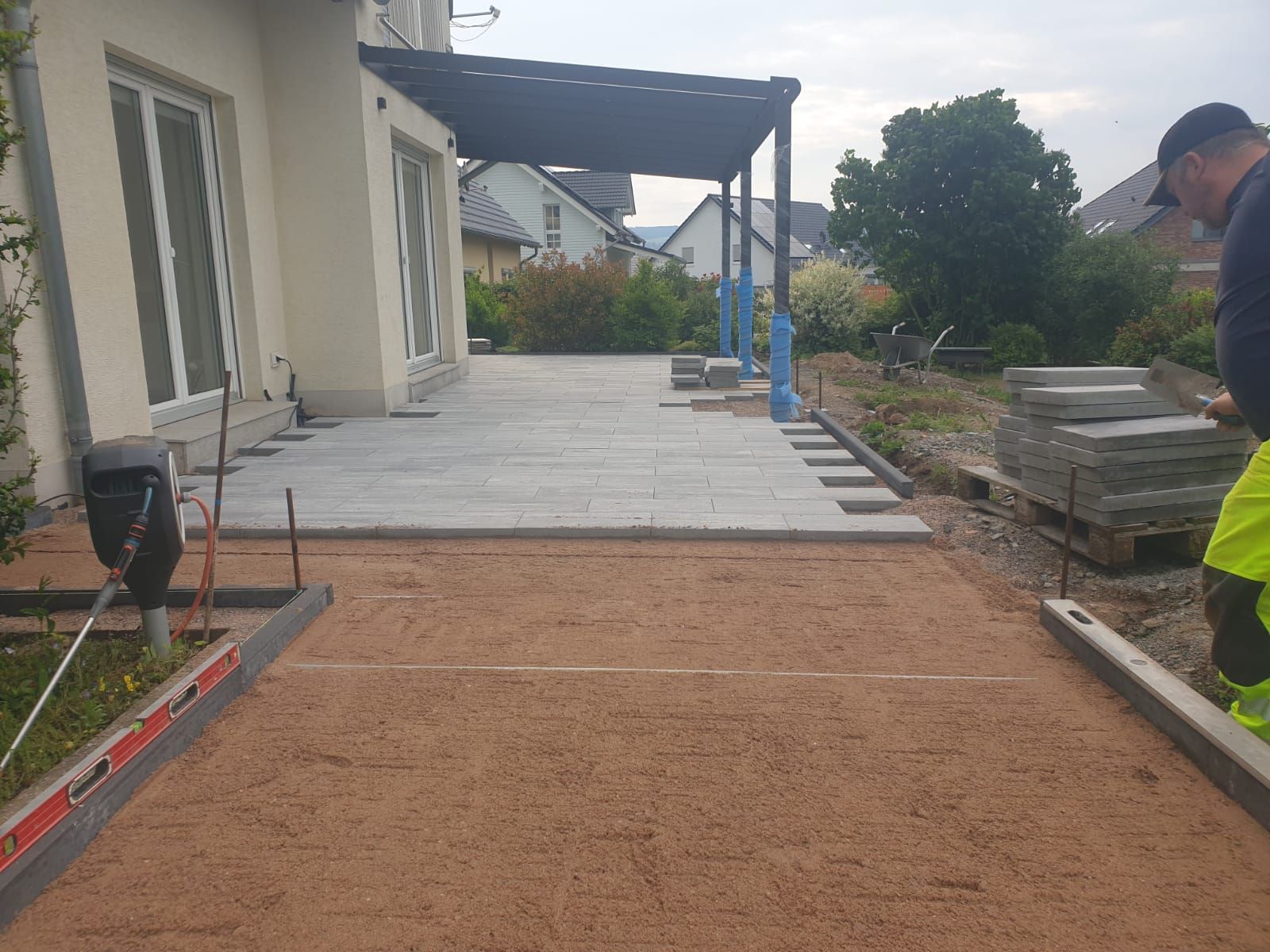 Ein Mann arbeitet an einer Terrasse vor einem Haus.