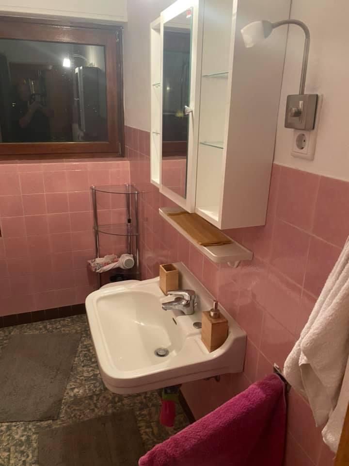 Ein Badezimmer mit rosa Fliesen, einem Waschbecken und einem Spiegel.