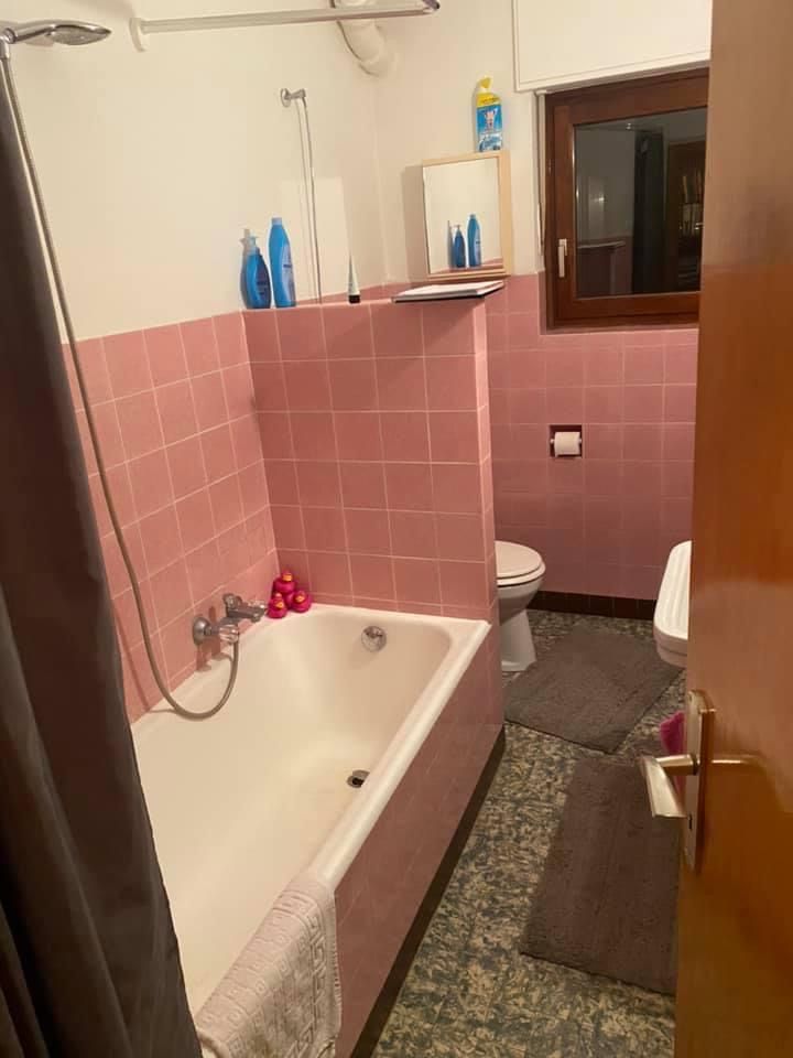 Ein Badezimmer mit rosa Fliesen und einer Badewanne und Toilette.