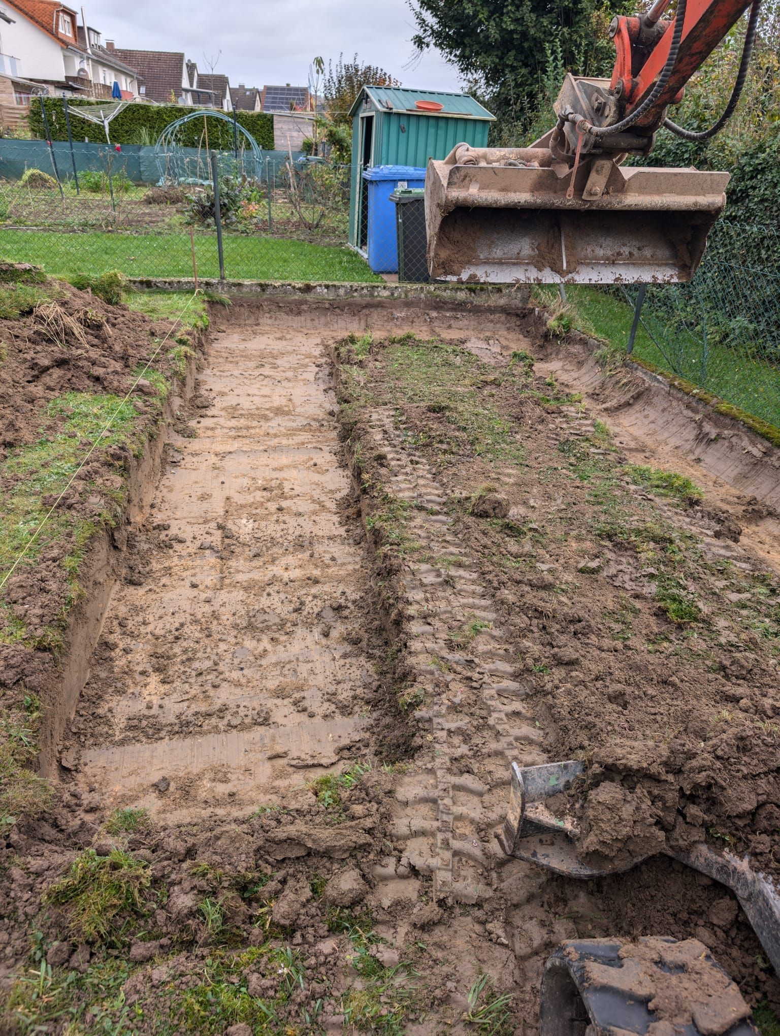 Ein Bagger gräbt in einem Hinterhof ein Loch in den Boden.