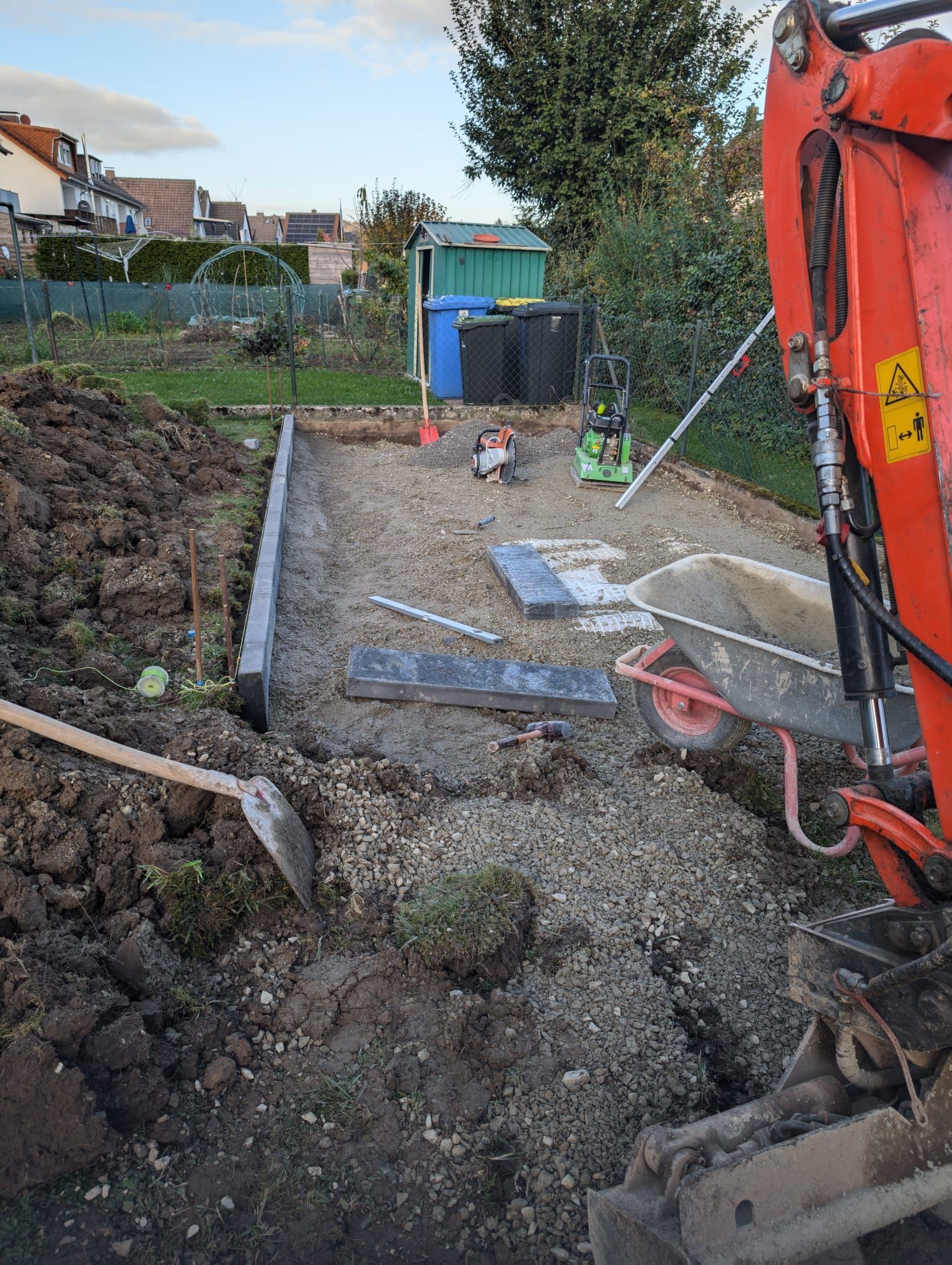 Eine Baustelle mit einer Schubkarre und einer Schaufel im Dreck.