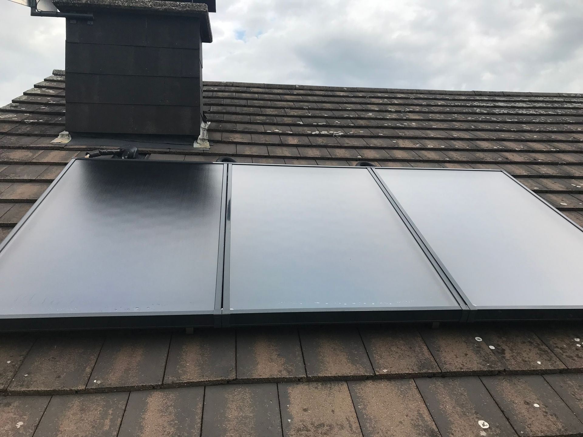 Ein Dach mit einem Schornstein und zwei Sonnenkollektoren darauf