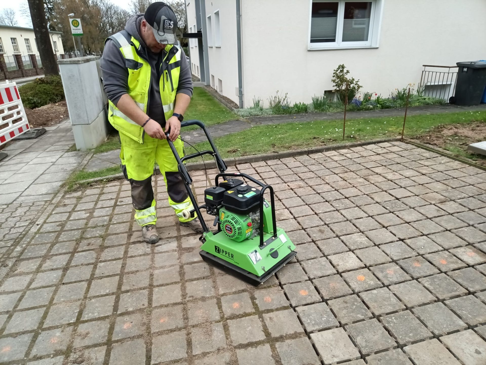 Ein Mann bedient eine Maschine auf einem Gehweg aus Ziegeln.