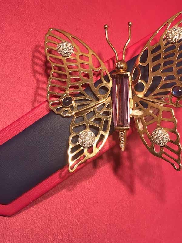 Un broche en forma de mariposa sobre fondo rojo.