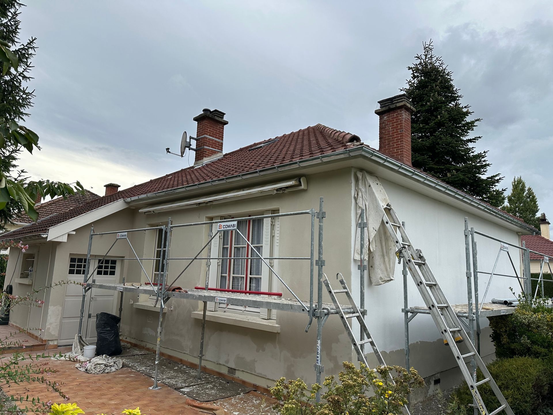 Maison de plain-pied avec échafaudages et rénovation extérieure en cours.