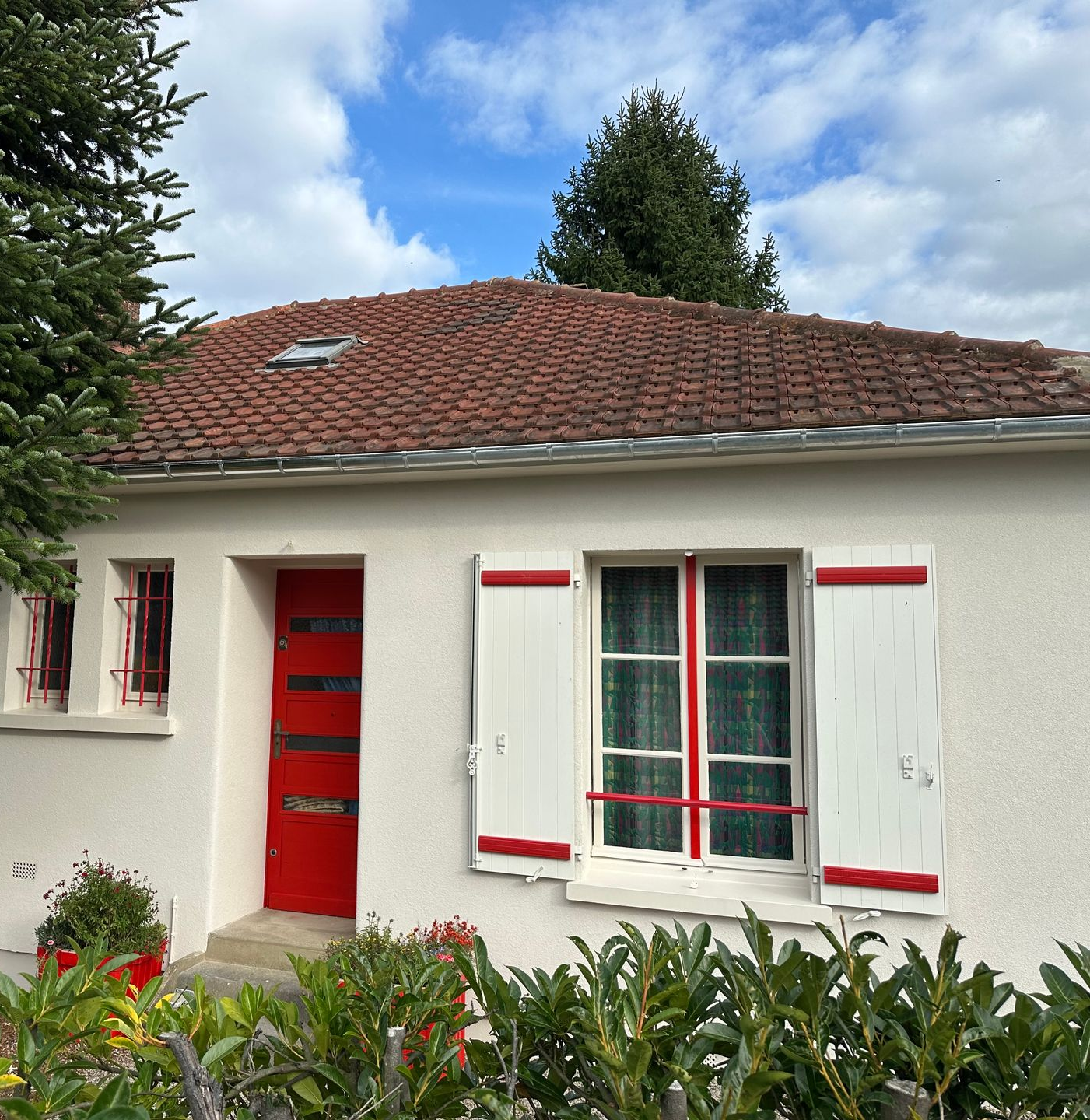 Maison avec porte et volets sous un toit de tuiles.